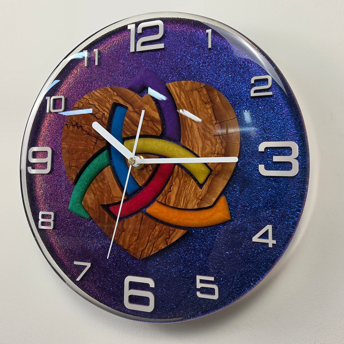 Close view of Woven Heart wall clock showing natural olive wood grain and colorful interwoven heart details.