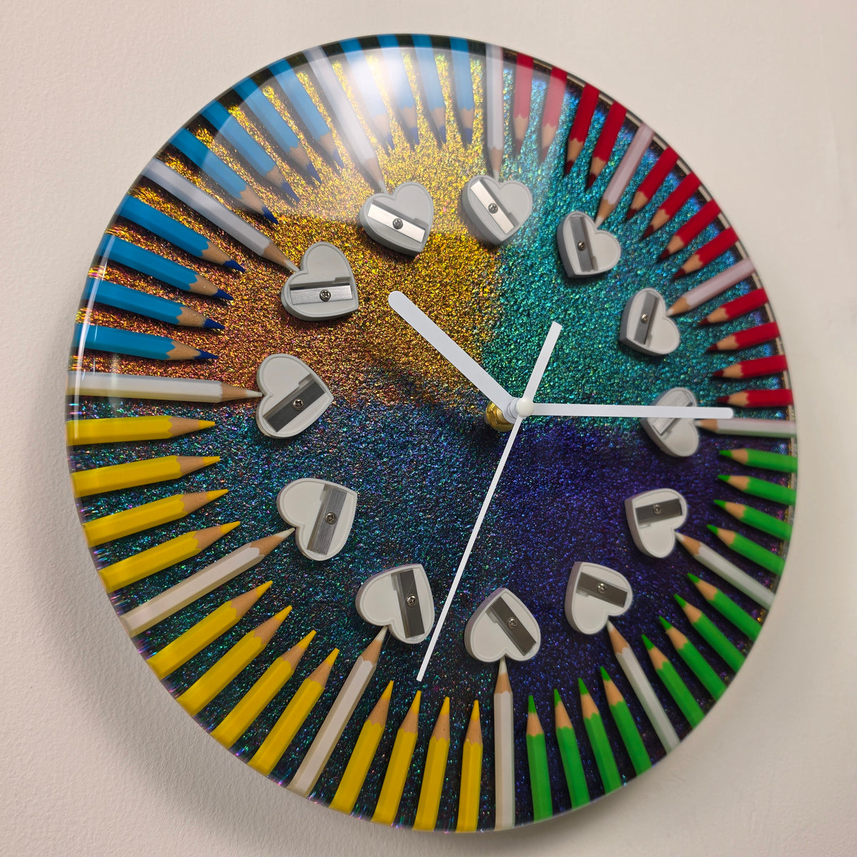 Colorful Four Seasons art clock with pencils embedded in clear epoxy resin and heart-shaped pencil sharpeners as hour markers.