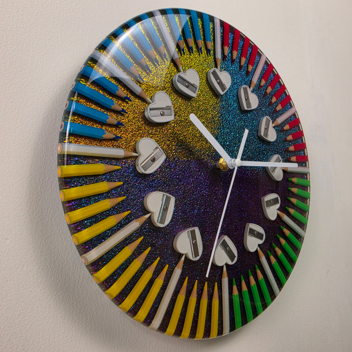 Close-up of a colorful resin art clock with four groups of pencils and heart-shaped pencil sharpener hour markers.