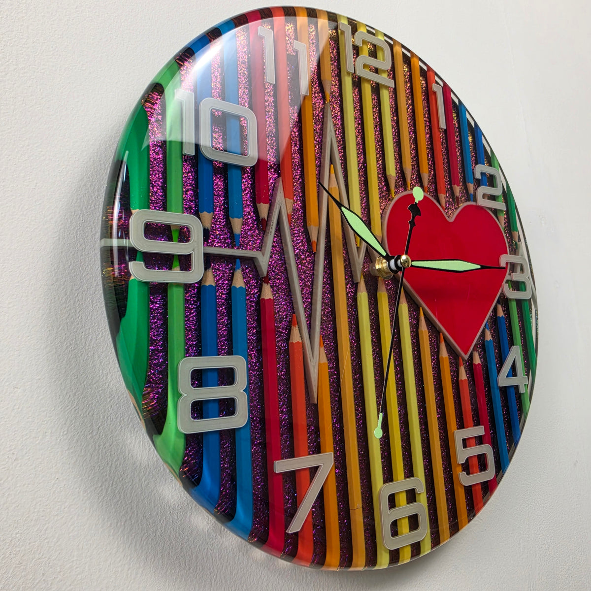 Unique handcrafted wall clock with colored pencils embedded in epoxy resin and a vibrant red heart centerpiece.