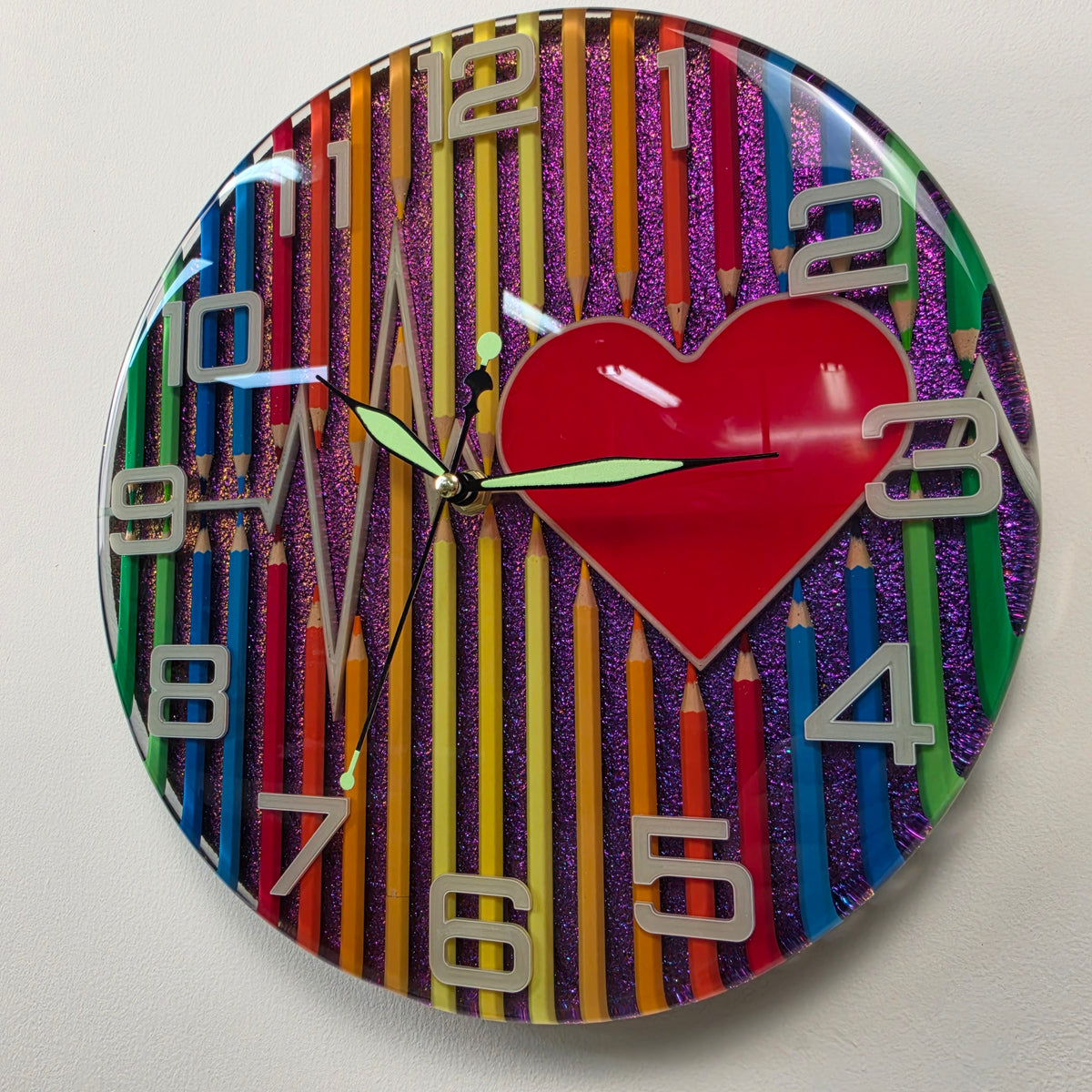 Colorful 30 cm resin wall clock with pencils, heart motif, white numbers and glossy epoxy finish.