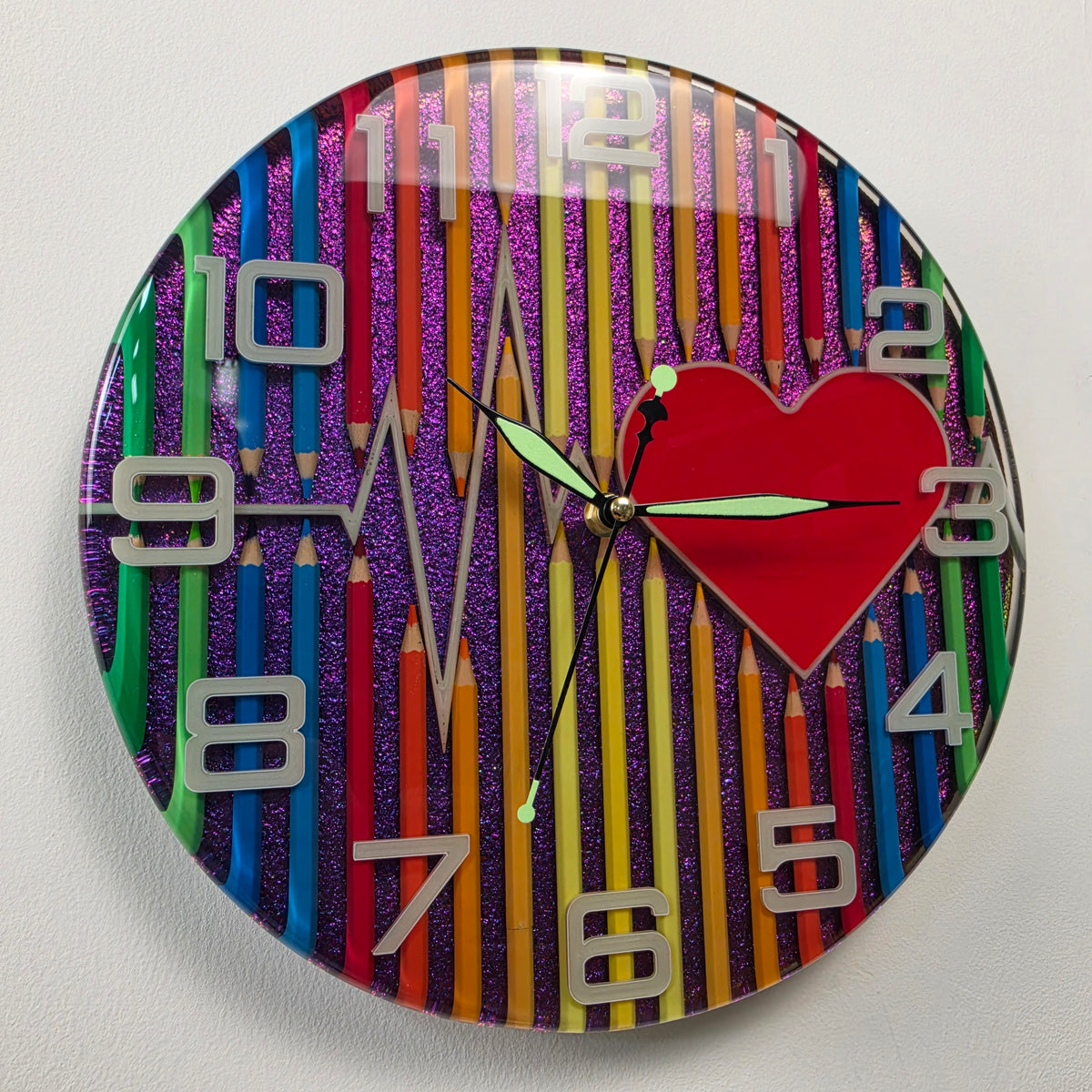 Handmade epoxy resin wall clock with colorful pencils, red heart and heartbeat design from the Studio Colors series.