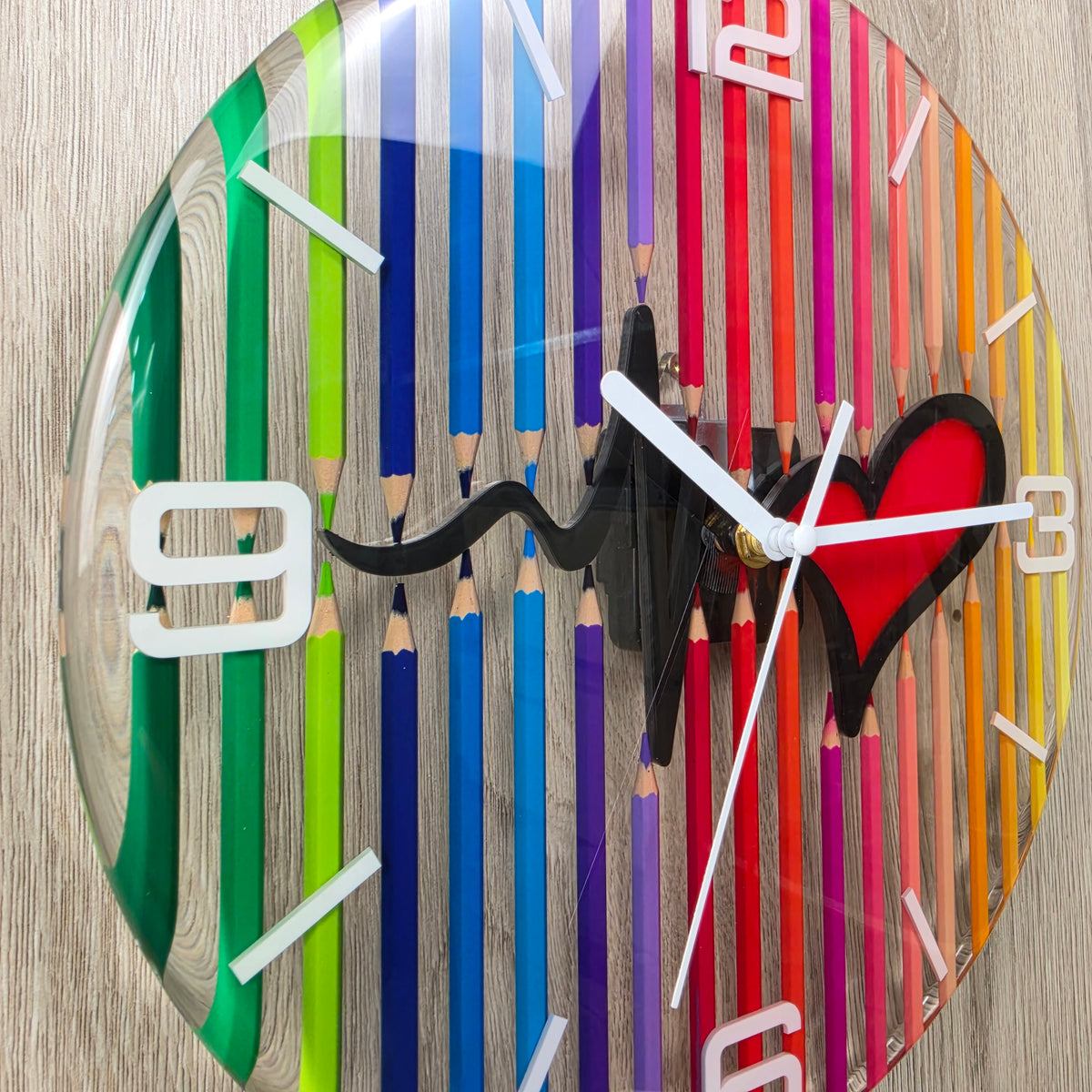 Transparent epoxy resin wall clock with rainbow colored pencils and red heartbeat heart