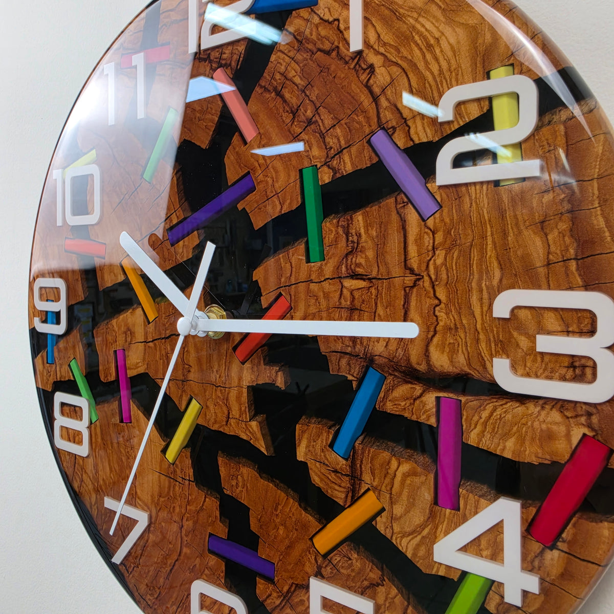 Broken Colors wall clock combining natural olive wood, black epoxy resin and vibrant colored pencil fragments.