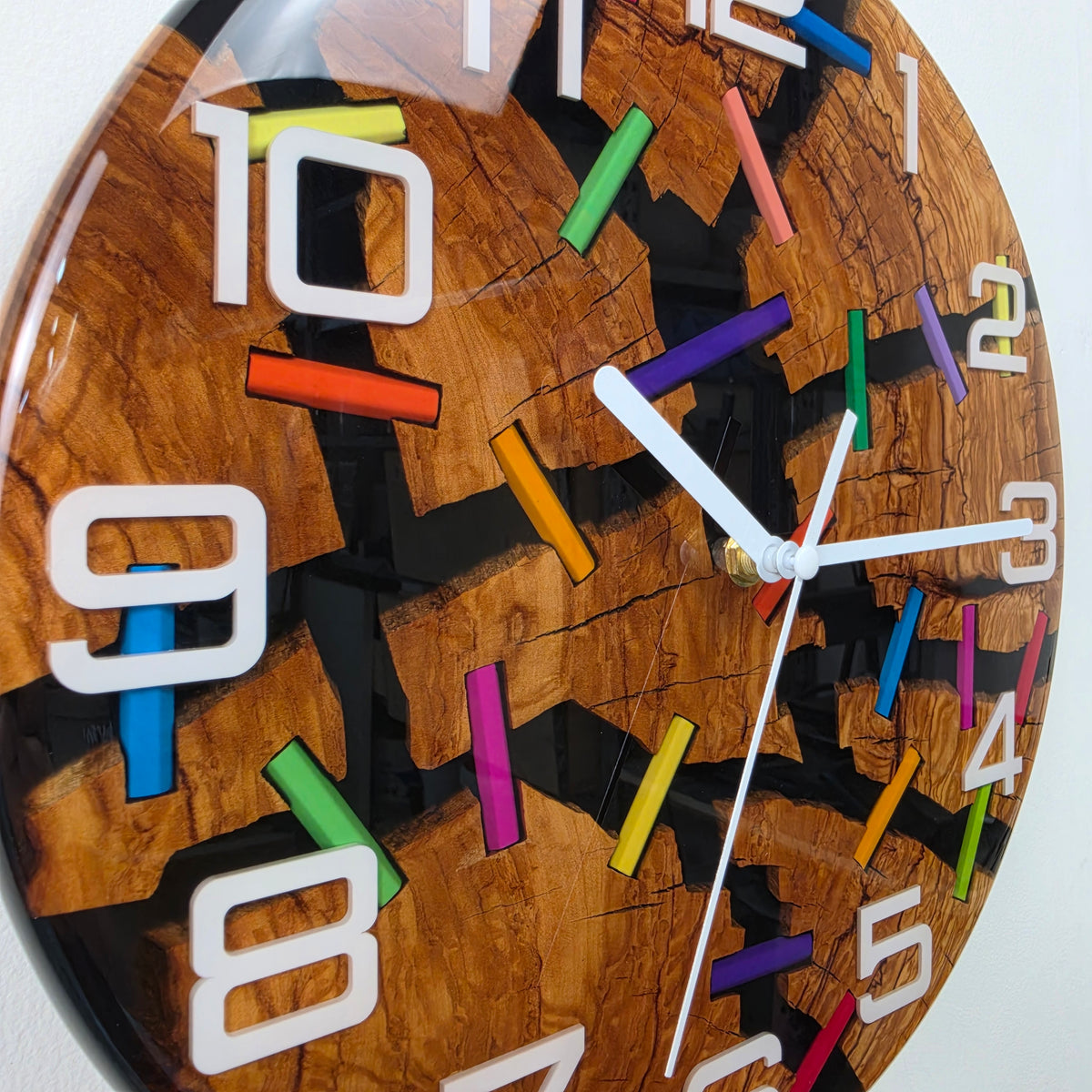 Artistic olive wood wall clock with natural cracks connected by colorful pencil fragments and black resin.