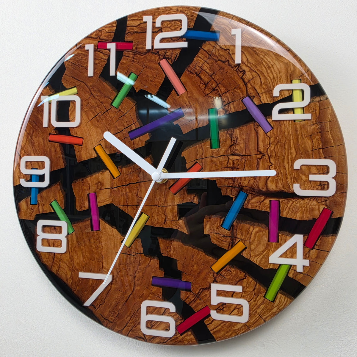 Modern wood and resin wall clock with expressive olive wood grain, black resin cracks and colorful pencil accents.