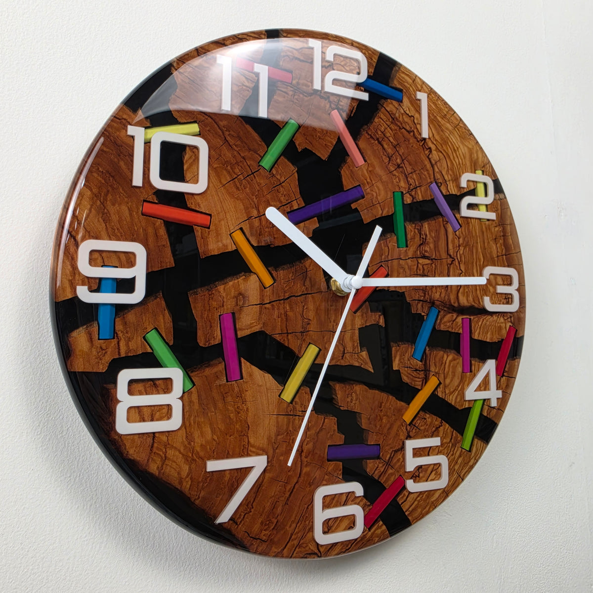 Unique handcrafted olive wood clock with colored pencil fragments creating bridges across natural wood cracks.