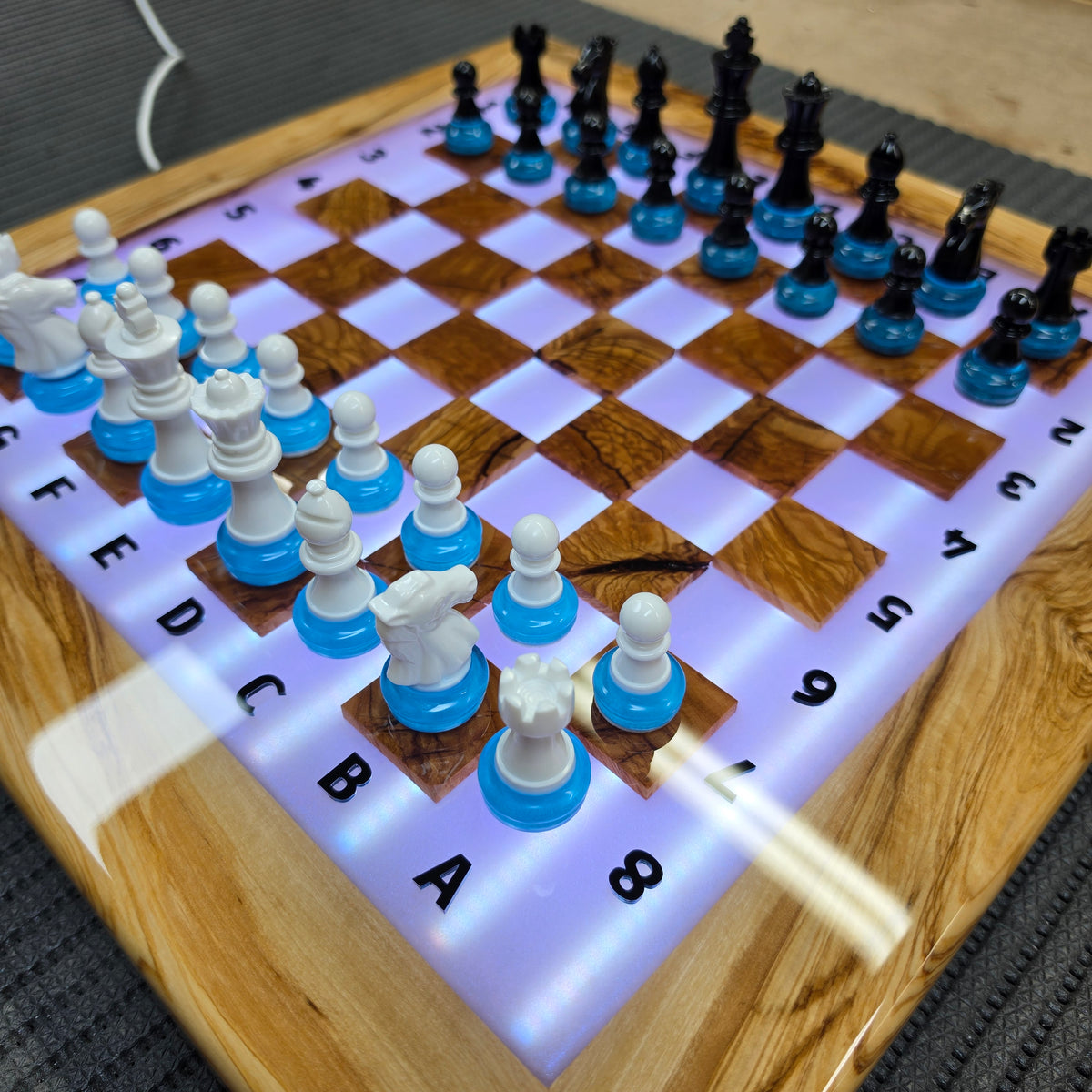 Illuminated epoxy resin chessboard handmade from natural olive wood