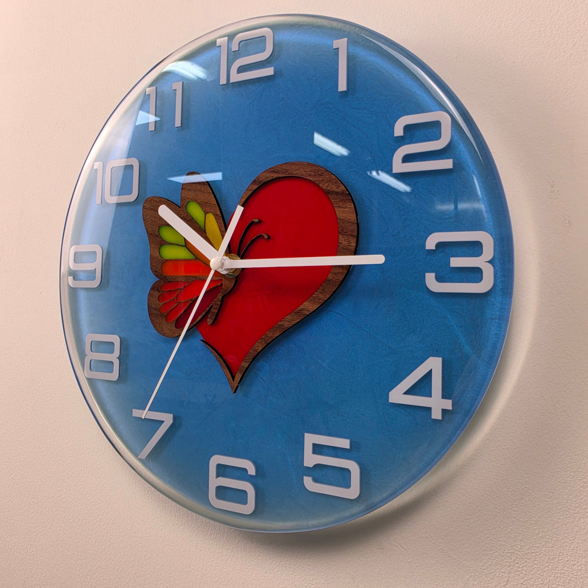 Unique handmade wall clock featuring a wooden heart and multicolored butterfly wing encapsulated in clear resin