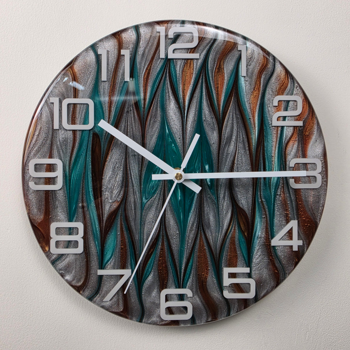 Close-up of shimmering turquoise, metallic silver and copper bronze pigments in a handmade resin clock.