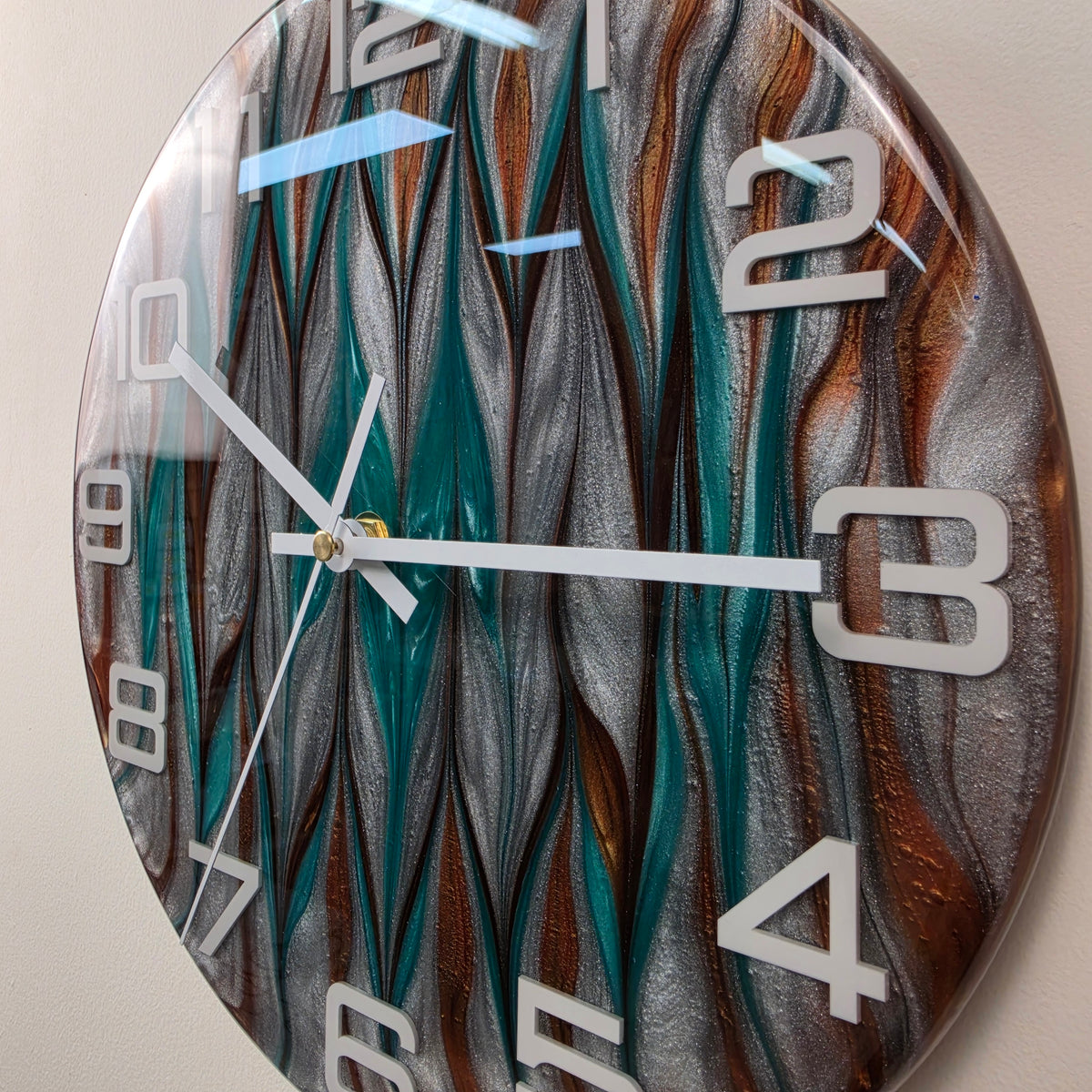 Unique modern wall clock with three-dimensional white numerals and elegant white hands against a metallic resin background.