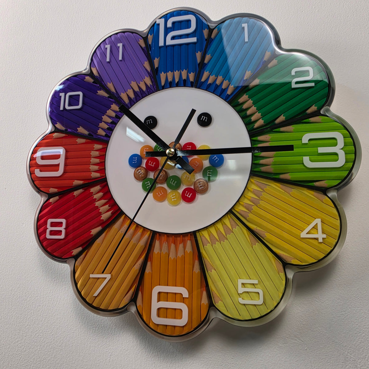 Close-up of the white clock center decorated with colorful M&M-inspired resin candy casts and two playful black eyes.