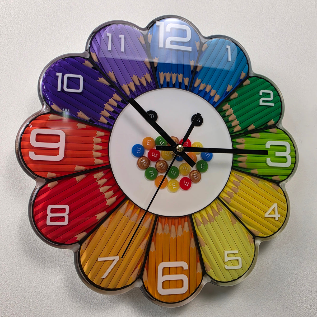 Handmade colored pencil wall clock featuring purple, blue, green, yellow, orange and red flower petals preserved in clear resin.