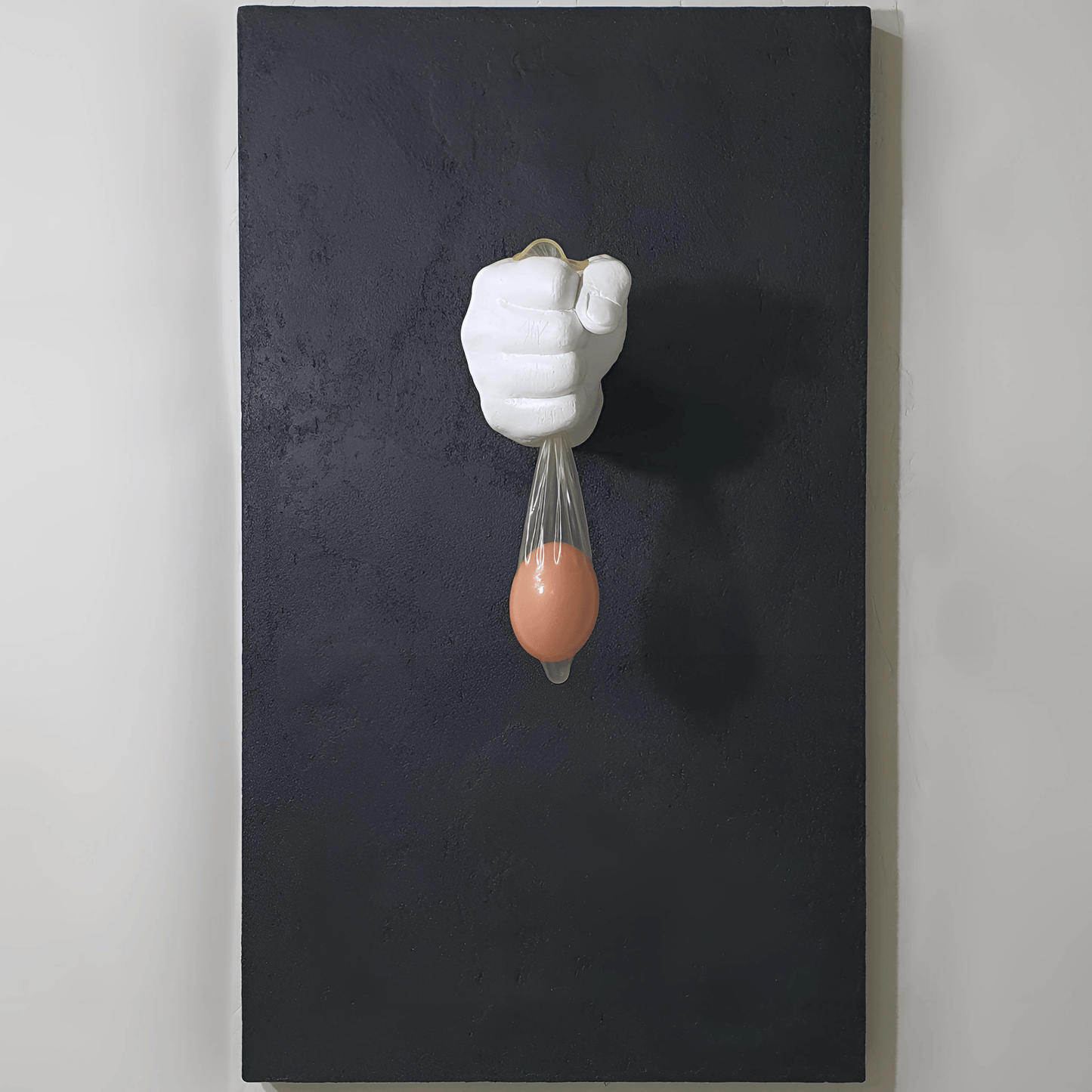Vita Protetta conceptual artwork – plaster hand holding condom with wooden egg, symbolic installation, front view