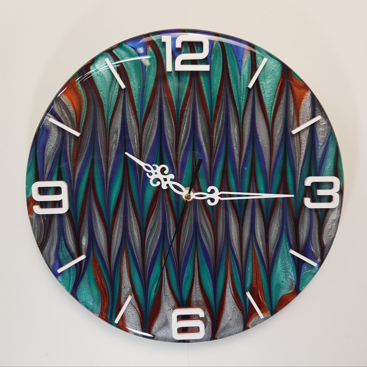 Front view of the “Aurora Stream” epoxy resin wall clock – round design with shimmering turquoise, navy, silver, and copper tones, and white plexiglass numbers.