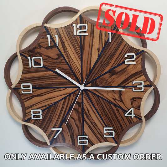 Front view of the Crown Circle wall clock – handcrafted from Zebrano, walnut, and maple wood, with deep blue epoxy resin.