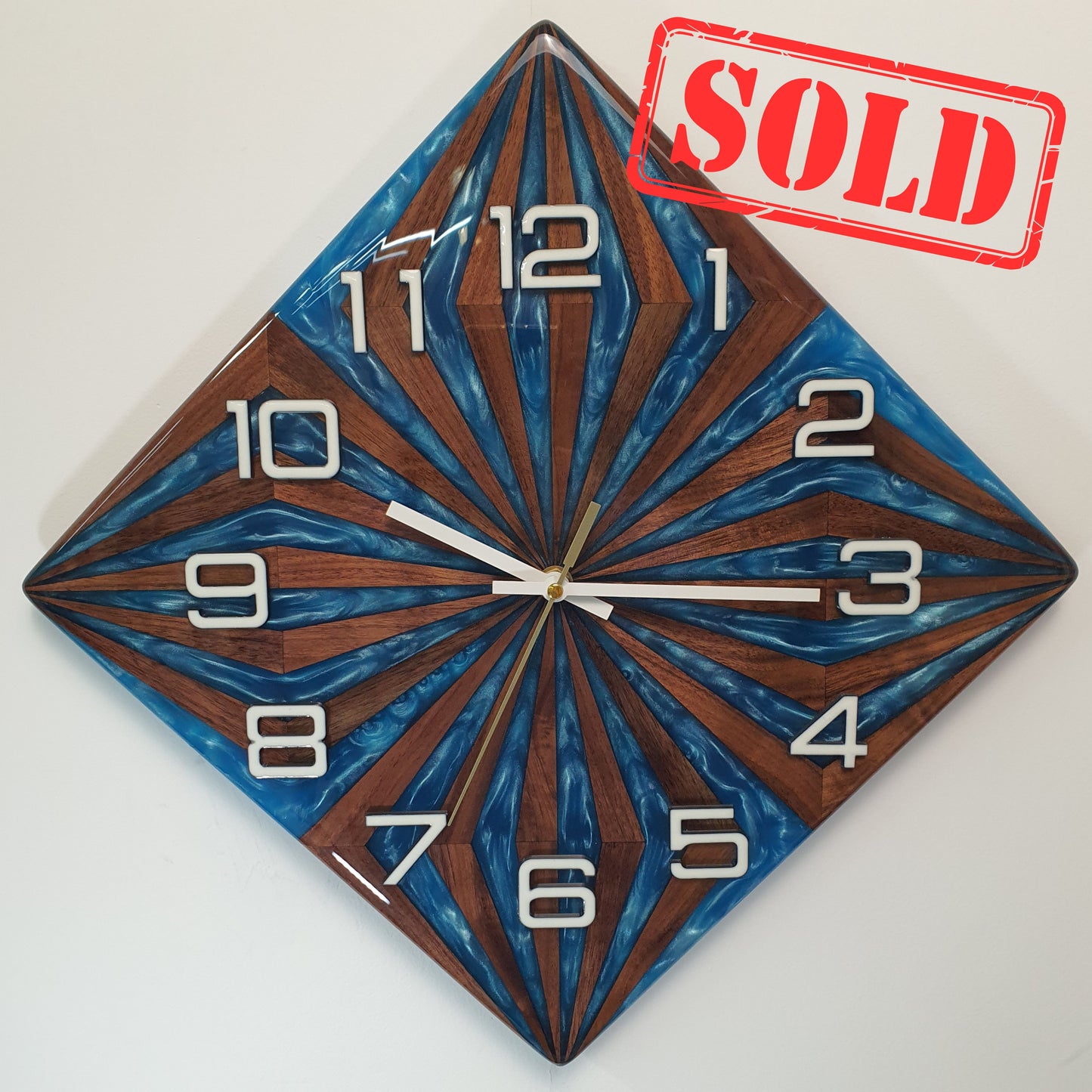Front view of the “Walnut Wave” wall clock – handcrafted from walnut wood and blue epoxy, geometric sunburst pattern