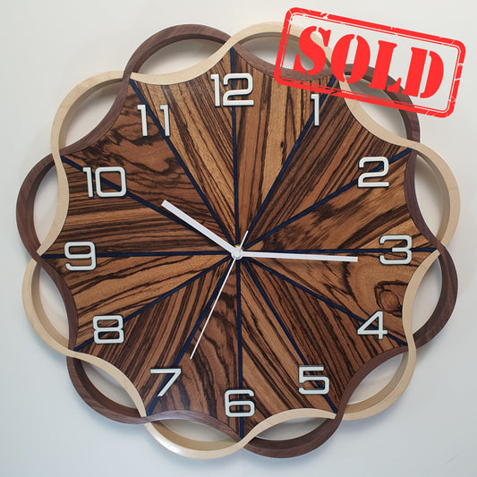 Front view of the Crown Circle wall clock – handcrafted from Zebrano, walnut, and maple wood, with deep blue epoxy resin.