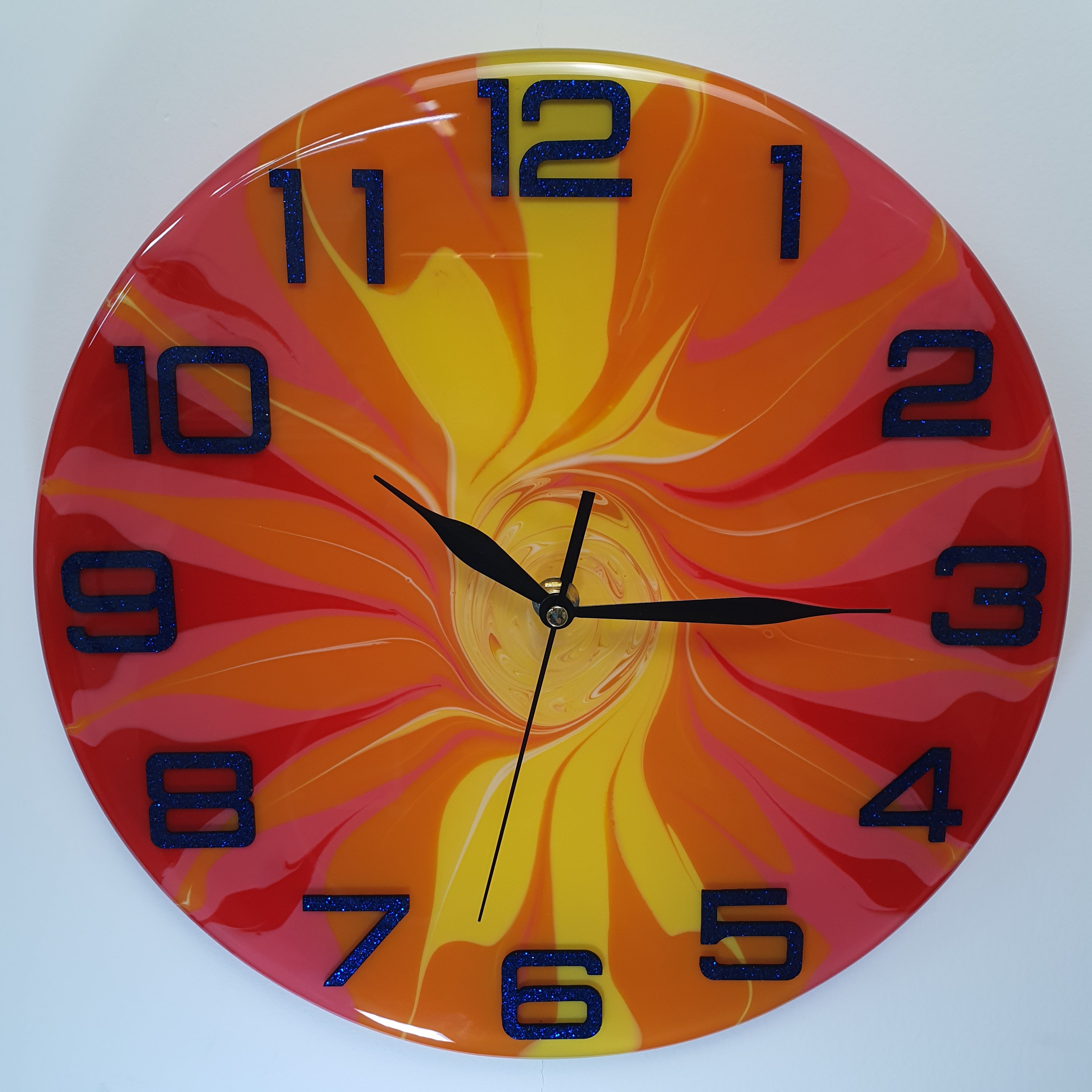 Front view of the "Fire Bloom" epoxy resin wall clock – bold swirling colors in red, orange, yellow, and pink