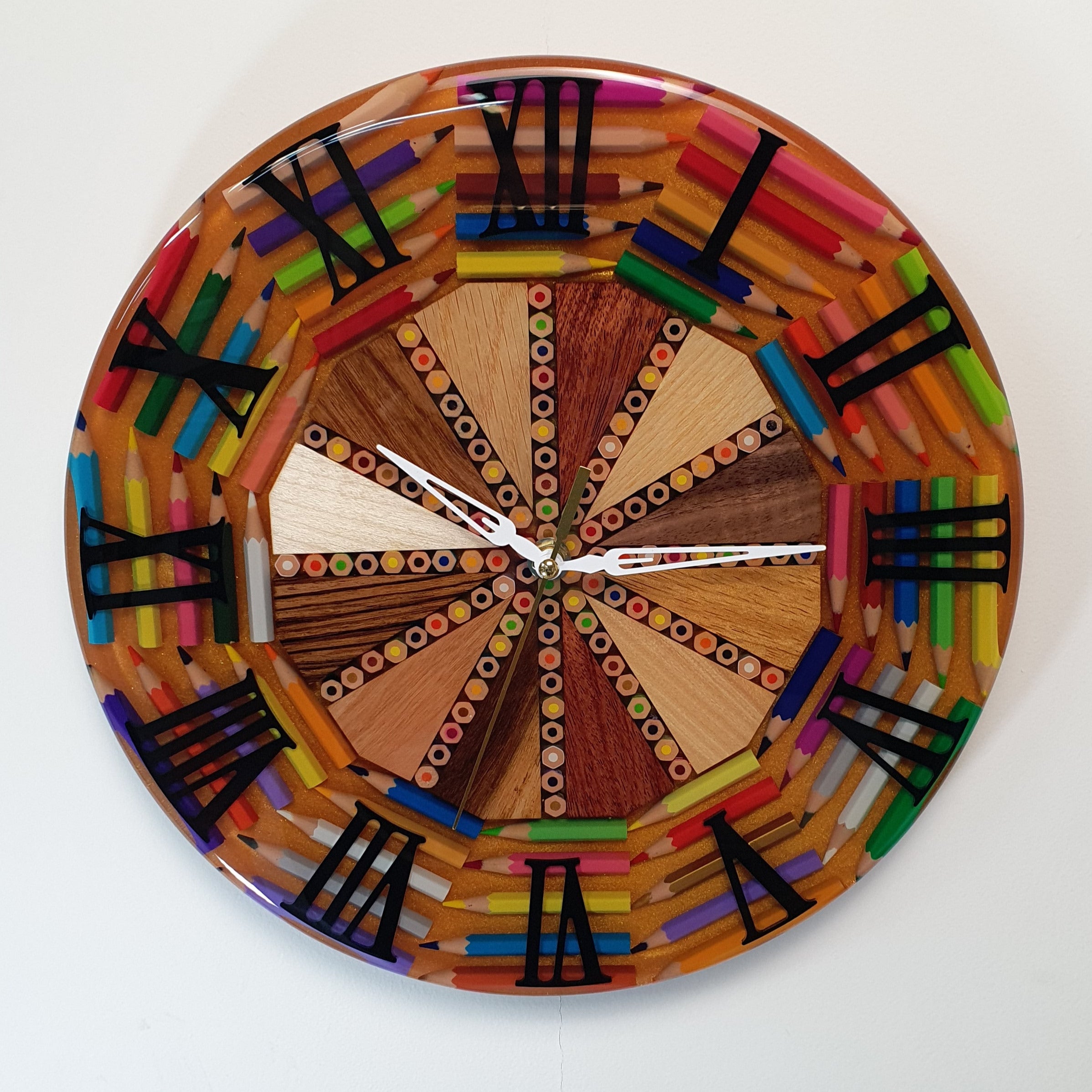Front view of the "Timber Pop" wall clock – handmade from wood, colored pencils, and epoxy resin, with bold black Roman numerals